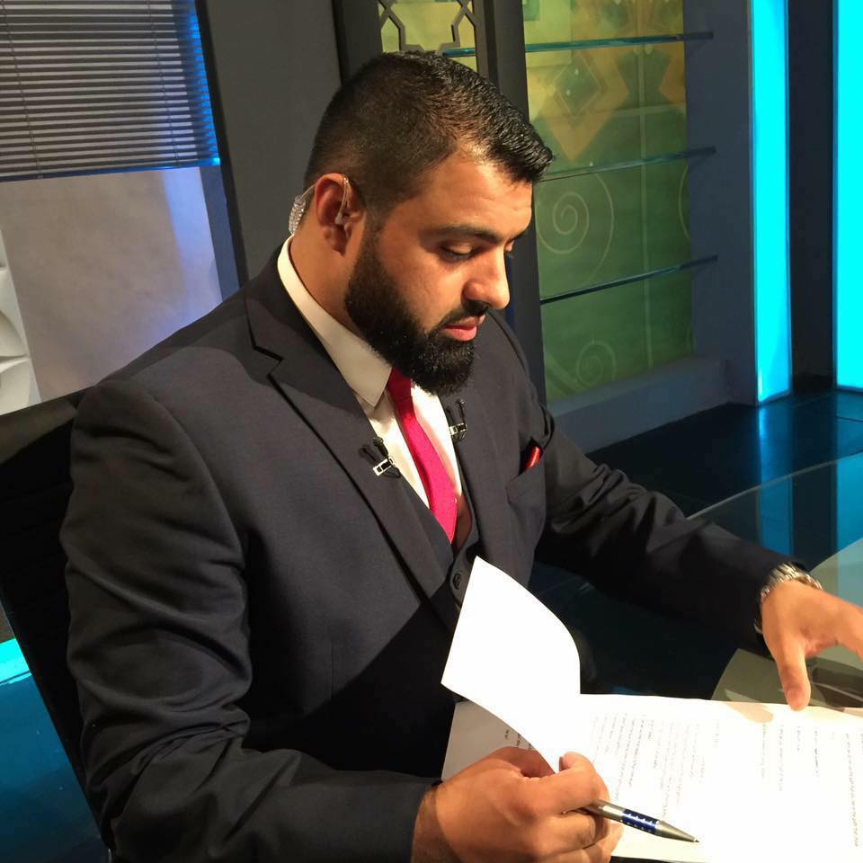 Sheikh Junaid Dar al-Azhary in a television studio, reviewing his notes.